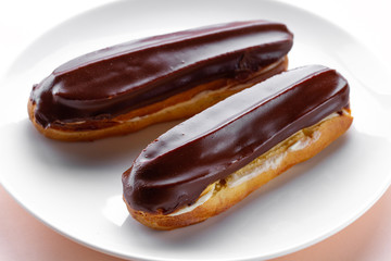 Traditional french dessert. Delicious eclairs with custard and chocolate icing for sweet tooth on a plate. Pastry products.