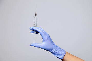 Closeup doctor hand in rubber latex medical purple glove hold transparent syringe with sharp...