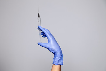 Closeup doctor's hand in rubber latex purple glove hold transparent syringe. Isolated on white...