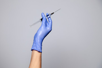 Closeup doctor or nurse hand in rubber latex medical purple glove holding a transparent syringe...