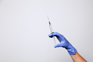 Closeup doctor or nurse hand in rubber latex medical purple glove holding a transparent syringe...