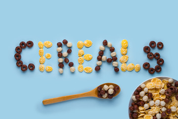 Cereals bowl and spoon on a blue background. Glazed, chocolate balls, rings and corn flakes for healthy dry breakfast. Cereals concept