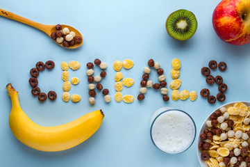Bowl and spoon with dry chocolate balls, rings, corn flakes, glass of milk and fresh ripe fruits...