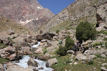Fototapeta na wymiar Man herding donkey by the river in the mountains, Fann Mountains, Tajikistan 