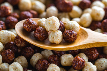 Cereals spoon with chocolate brown and white balls for dry breakfast close up.