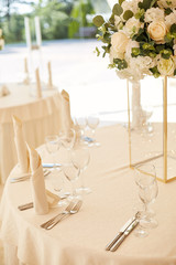 Dining table with a beautiful glass vase decorated with a bouquet of white flowers at a wedding ceremony.