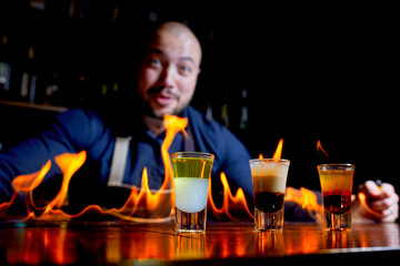 Fiery show at the bar. The bartender makes hot alcoholic cocktail and ignites bar. Bartender prepares a fiery cocktail. Fire on bar.