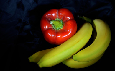 natura morta. composizione con peperoni e banane, sfondo nero.