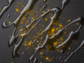 Dark food background with curry spices and oil on fluoroplastic frying pan, macro, close-up, top view