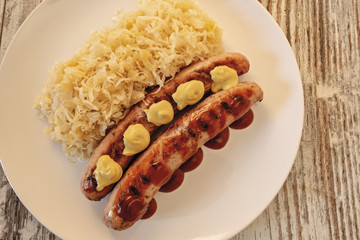 wurstel e crauti nel piatto con salsa barbecue e senape dall'alto