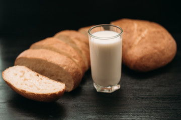 Ciabatta and a glass of milk on a wooden background.