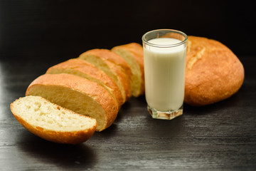 Ciabatta and a glass of milk on a wooden background.