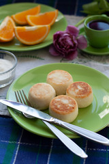 Delicious Dietary Cheesecakes from Homemade Farmer's Cheese for breakfast, black coffee in a green cup, chopped orange and.and purple tulip on a blue tablecloth