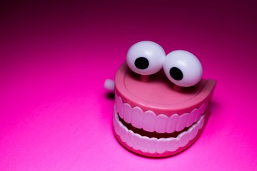 wind up teeth and eyeballs joke toy on pink background