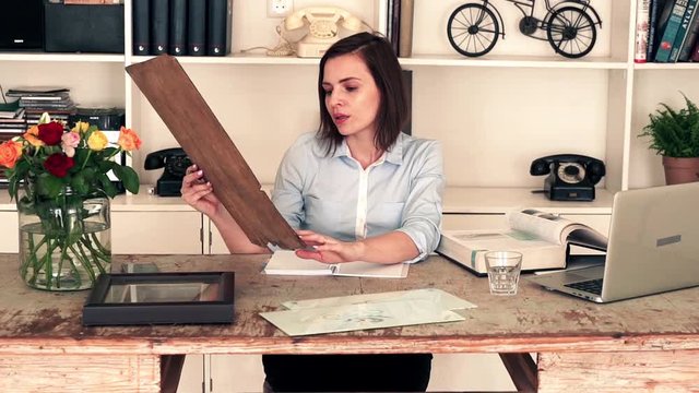 Young art curator looking at painting and doing notes.