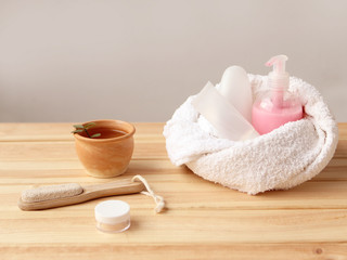 Rolled towel, cosmetic bottles on a light wooden background. Health and beauty concept