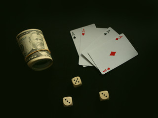 Fototapeta na wymiar Dollar bills lie in rolls on a black background. Nearby are the dice and cards. Concept business, strategy, winning, game