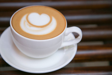 coffee cuppacino on wooden table in white cup with white heart froth