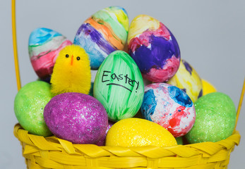 a basket of coloured eggs and toy chicks are shown ahead of Easter