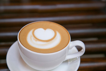 coffee cuppacino on wooden table in white cup with white heart froth