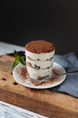 Italian dessert tiramisu closeup on wooden table, mint