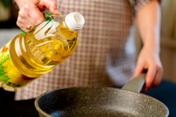 woman pouring oil on the frying pan