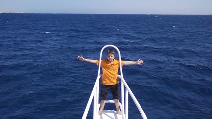 Adorable boy standing on the yacht bow