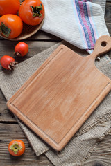 Rustic composition with different varieties of persimmons and wooden cutting board. Country style. Baking or cooking background. Copy space for text, menu, recipes
