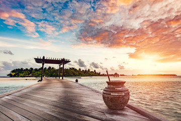 Wooden jetty on a blue ocean at sunset.
