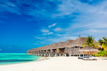 Tropical beach with straw cabins on Maldives.