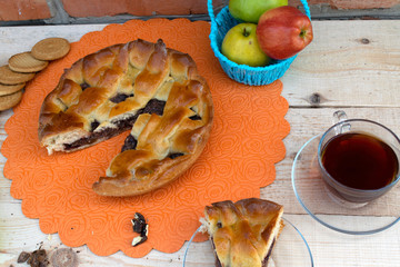 pie, a slice of apple pie with cherry and walnuts, a cup of tea, apples in a basket, walnuts and...
