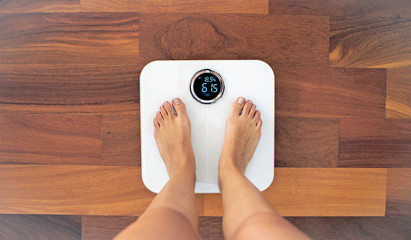 Woman bare feet standing on a digital scale with body fat analyzer that uses bioelectrical impedance (BIA) to gauge the amount of fat in your body