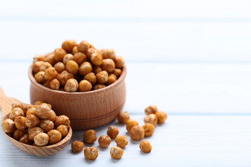 Roasted chickpeas in spoon and bowl on wooden table