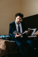 businessman holding folder with documents on bed with suitcase