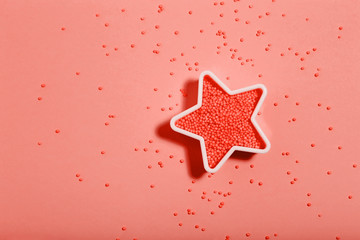 Fototapeta na wymiar Star with sprinkles on living coral color background. Minimalism concept
