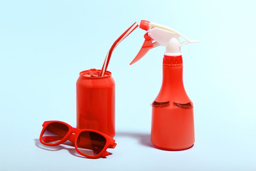 Obraz premium Aluminum can with sunglasses and spray bottle on blue background. Minimalism concept