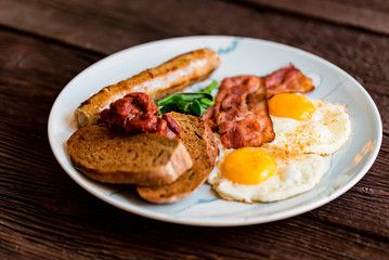 Typial breakfast with eggs, bacon and sausage on plate