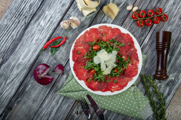 close-up carpaccio meat with arugula and slices of parmesan cheese