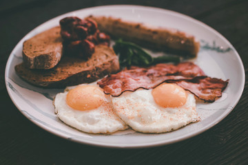 Typial breakfast with eggs, bacon and sausage on plate