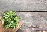 Green basil leafs with cutting board on grey wooden table