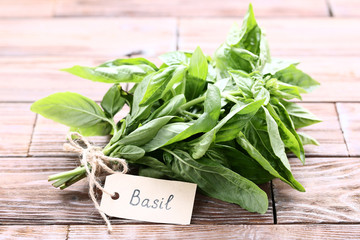 Green basil leafs with paper card on brown wooden table
