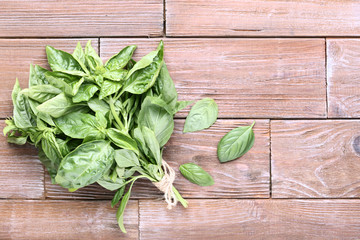 Fototapeta premium Green basil leafs on brown wooden table