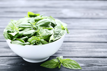 Green basil leafs in bowl on black wooden table