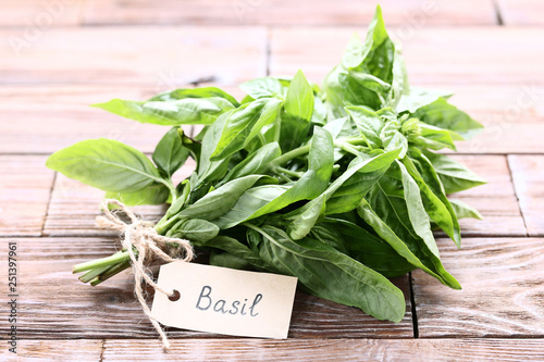 Green basil leafs with paper card on brown wooden table