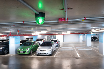Indoor parking lot building blurred background and green light for One place is free, car park system technology concept.