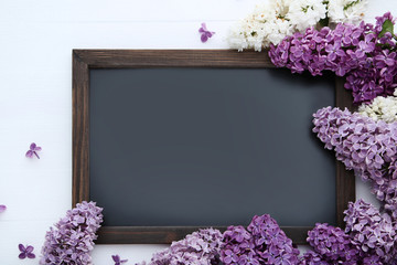 Purple lilac flowers with black frame on wooden table