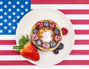 Heap of pancakes with berries on USA flag