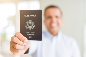 Middle age man holding holding passport of United States with a happy face standing and smiling with a confident smile showing teeth