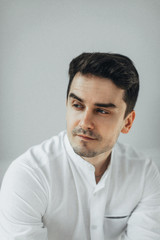 Obraz premium Fashion portrait of handsome man with dark beard and hair, weared in white shirt