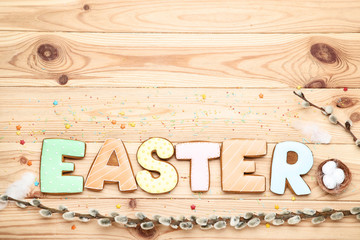 Word Easter by gingerbread cookies with willow branch and sprinkles on wooden table
